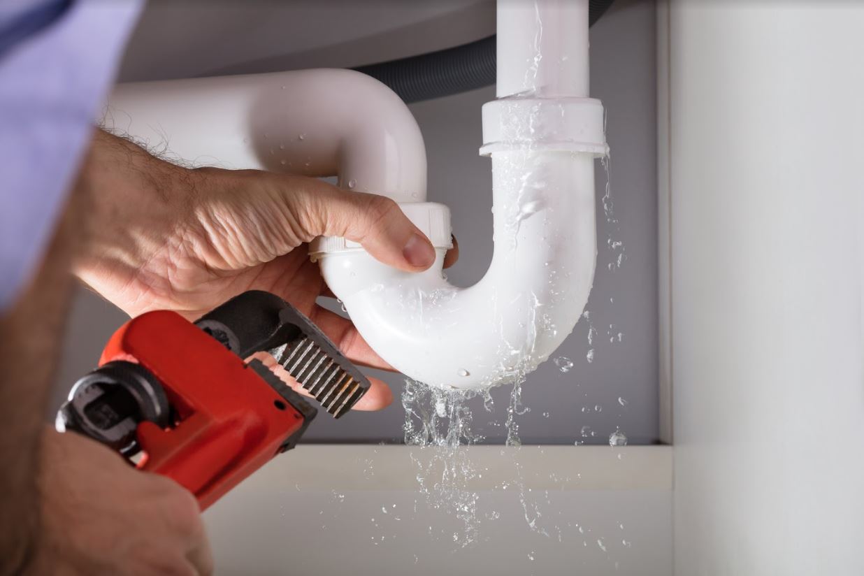 Technician repairing a leaking white pipe.