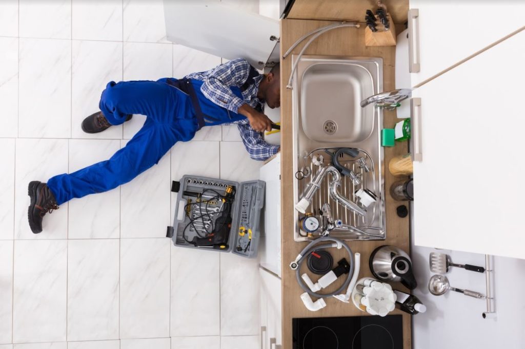 Plumber under sink making repairs