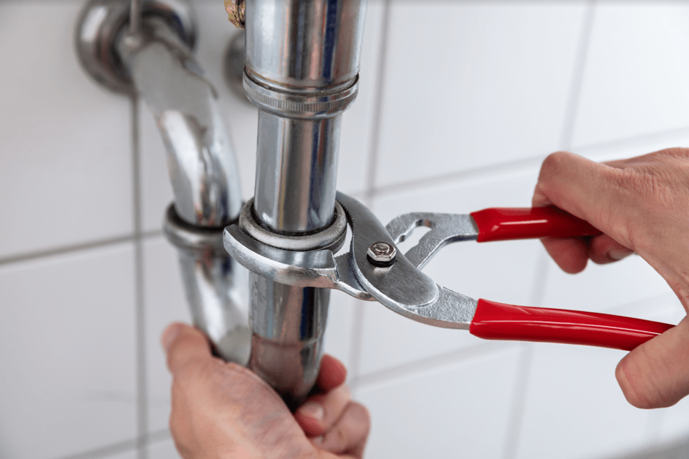 A plumber repairing a leaky pipe with a wrench