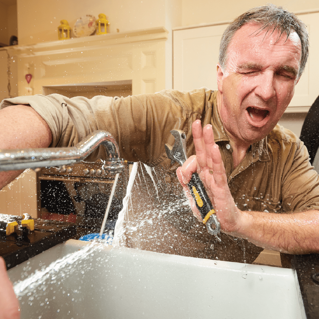 closeup of man being sprayed with water from a broken sink