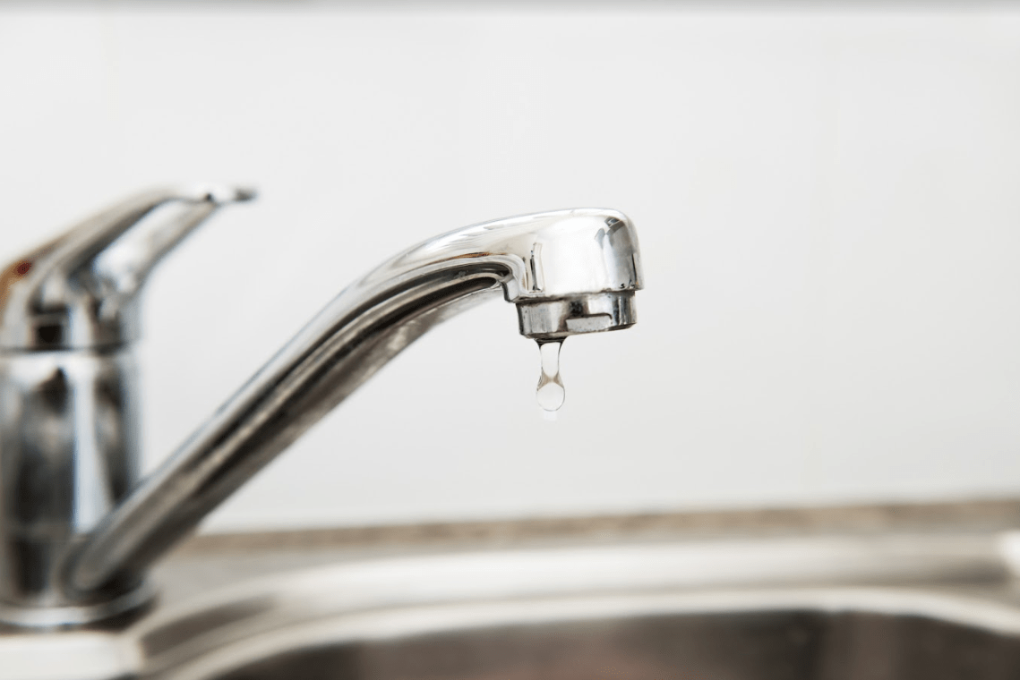 Close-up of dripping kitchen sink faucet.